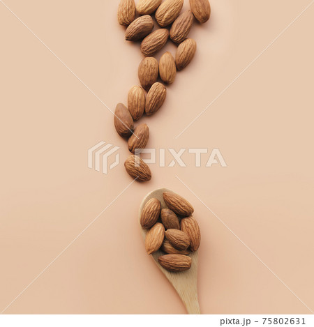 Raw almond kernels in spoon, beige background. Cosmetic, healthy food concept 75802631