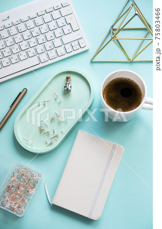 Lady freelancer's home pastel blue workplace, cup of coffee and computer keyboard on tabletop Lady freelancer's home pastel blue workplace, cup of coffee and computer keyboard on tabletop 75803466