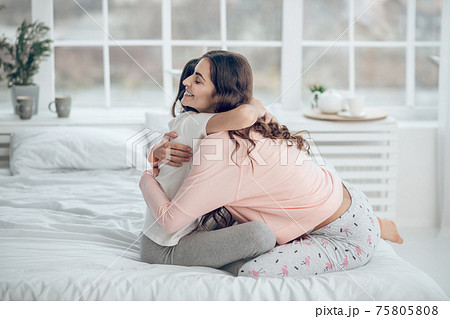 Mom and daughter hugging on bed in morning 75805808