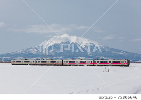 岩木山を背景に冬の津軽平野を走る電車 75806646
