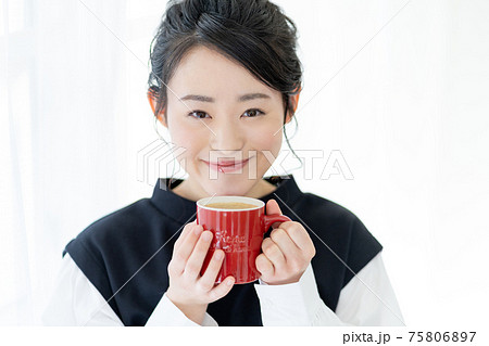 赤いマグカップでカフェオレを飲む若い女性の顔のアップ 赤いマグカップでカフェオレを飲む若い女性の顔のアップ 75806897