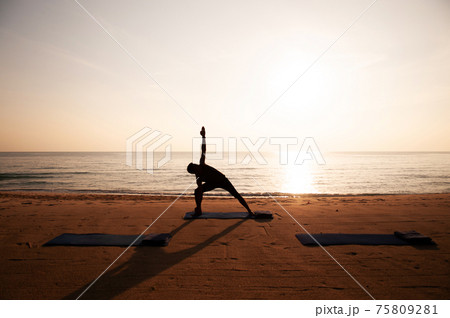Morning Yoga against rising sun on the beach Morning Yoga against rising sun on the beach 75809281