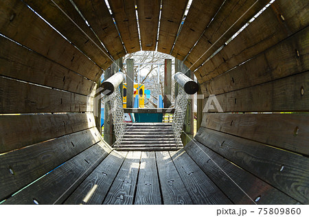 公園の木造遊具の円いトンネルの中から外の景色が見える構図の写真素材