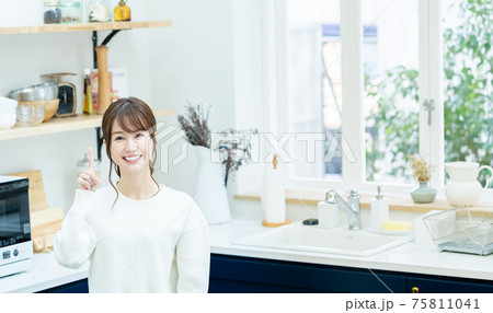 キッチンで指差しポーズをする若い女性 75811041