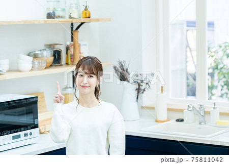 キッチンで指差しポーズをする若い女性 キッチンで指差しポーズをする若い女性 75811042