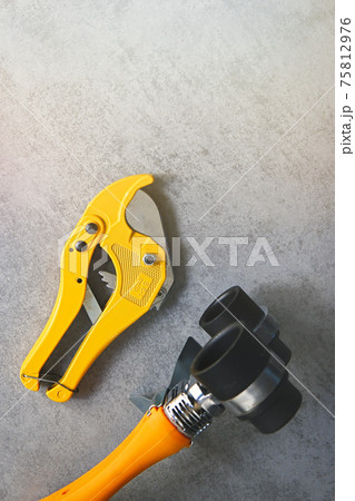 Yellow soldering iron for PVC pipes and pipe cutting scissors, plumbing tools for water supply on a grey background. Yellow soldering iron for PVC pipes and pipe cutting scissors, plumbing tools for water supply on a grey background. 75812976