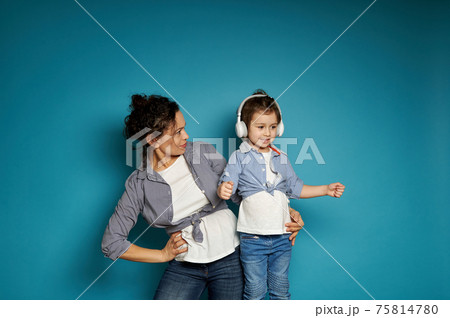 Mother hugging her daughter, posing over blue background 75814780