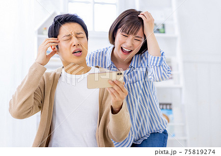 男女　スマホ　悔しがるイメージ 75819274