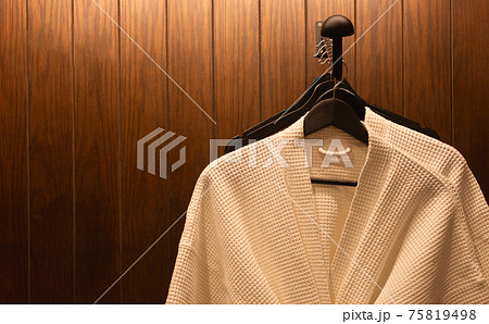 white bathrobes hanging in wooden wardrobe at night white bathrobes hanging in wooden wardrobe at night 75819498