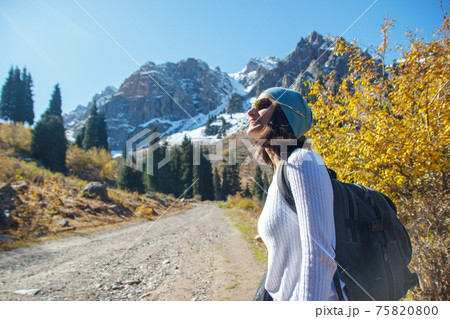 A smiling woman is looking up at the sky. Walk in the autumn in the mountains. 75820800