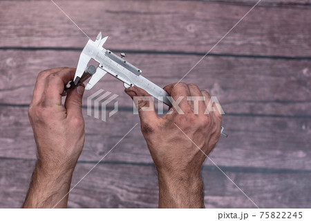 The worker measures the diameter of the drill with a caliper. 75822245