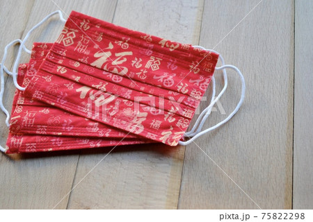Red color mask with Chinese Luck character in different writing styles on wooden background for social distancing of Chinese New Year in February. Copy space 75822298