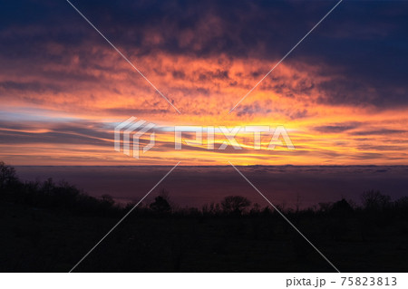 Amazingly beautiful sunrise over sea. breathtaking colors in sky from rising sun. Silhouette of coast against background of glowing clouds 75823813