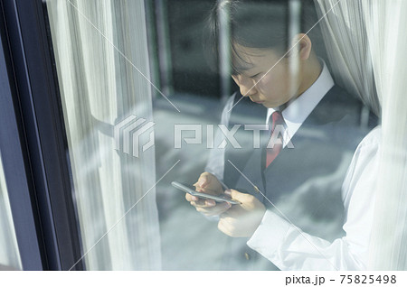 窓辺でスマートフォンを見る中学生（外出自粛要請のイメージ） 75825498
