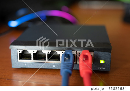 Close-up shot of a router - a red cable is connected next to the blue Ethernet cable. Concept of cabling, internet network, working with internet network. Operation and maintenance 75825684