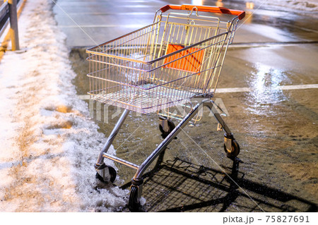 An abandoned shopping cart standing on the street near supermarket in the winter. An abandoned shopping cart standing on the street near supermarket in the winter. 75827691