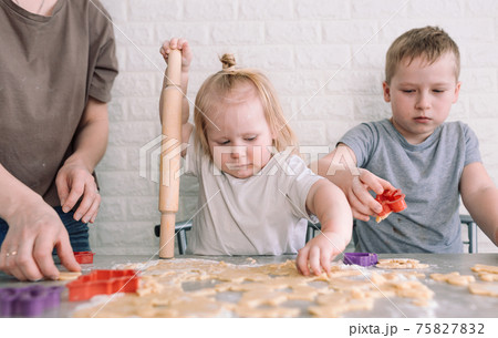little girl and boy help mom in the kitchen to cook delicious cookies little girl and boy help mom in the kitchen to cook delicious cookies 75827832