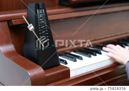 アップライトピアノを弾く女の子の指とメトロノーム アップライトピアノを弾く女の子の指とメトロノーム 75828356