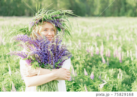A hippy girl holding bouquet of wildflowers in her hands. Girl hid her face behind bouquet of lupins A hippy girl holding bouquet of wildflowers in her hands. Girl hid her face behind bouquet of lupins 75829168