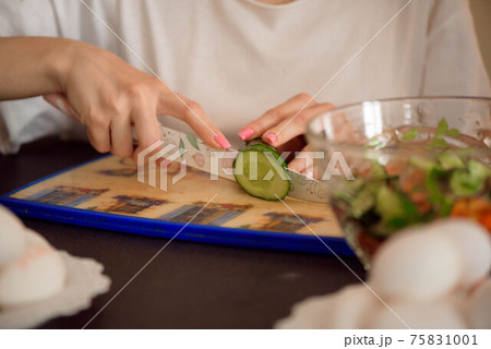 Young girlfriends chopping vegetables with twin in a family home kitchen. Young girlfriends chopping vegetables with twin in a family home kitchen. 75831001