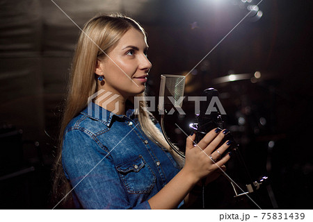Female singer singing a song. Woman performing in a recording st Female singer singing a song. Woman performing in a recording st 75831439