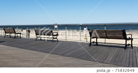 Three park benches on a boardwalk by the beach 75832649