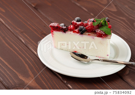 Piece of berry cheesecake served on brown wooden table 75834092