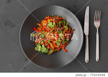 Top view of wok noodles with vegetables and meat in bowl on gray background 75834098