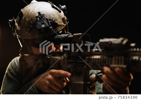 US special forces soldier looking at the aim ready to shoot against black dark background US special forces soldier looking at the aim ready to shoot against black dark background 75834390