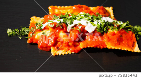 Four cheese filled ravioli in a tomato and basil sauce on the black stone plate Four cheese filled ravioli in a tomato and basil sauce on the black stone plate 75835443