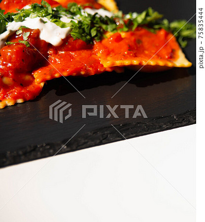 Four cheese filled ravioli in a tomato and basil sauce on the black stone plate Four cheese filled ravioli in a tomato and basil sauce on the black stone plate 75835444