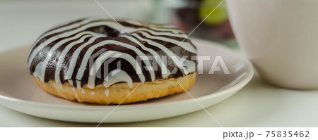 Doughnut with chocolate flavour filling, topped with white and black icing 75835462