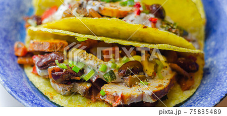 Mexican tacos shells with chicken and red kidney beans, onion,  red and green peppers, and salsa sauce 75835489