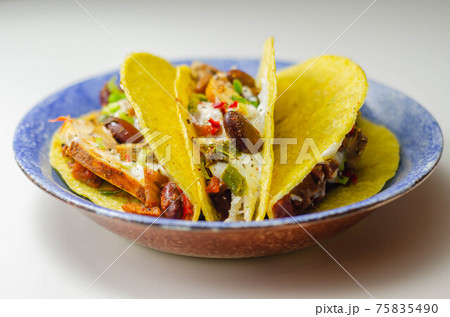 Mexican tacos shells with chicken and red kidney beans, onion, red and green peppers, and salsa sauce Mexican tacos shells with chicken and red kidney beans, onion, red and green peppers, and salsa sauce 75835490