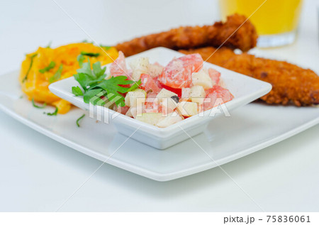 Breaded and herbed chicken breast fillet served with mashed carrots with potatoes and tomato salad with onions Breaded and herbed chicken breast fillet served with mashed carrots with potatoes and tomato salad with onions 75836061