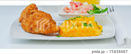 Breaded and herbed chicken breast fillet served with mashed carrots with potatoes and tomato salad with onions Breaded and herbed chicken breast fillet served with mashed carrots with potatoes and tomato salad with onions 75836067