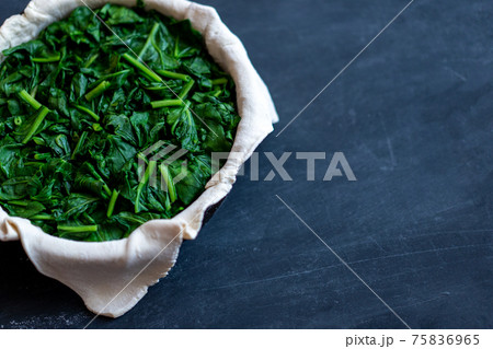 raw spinach pie preparation Standing wooden table background 75836965