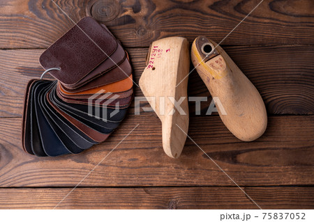 Leather samples for shoes and wooden shoe last on dark wooden table. Leather samples for shoes and wooden shoe last on dark wooden table. 75837052