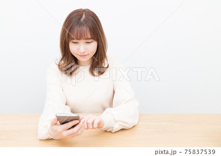 机でスマートフォンを使う女性 75837539