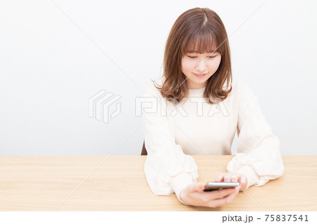 机でスマートフォンを使う女性 75837541