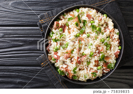 Arborio rice with green peas and prosciutto Italian risotto close-up on the table. horizontal top view Arborio rice with green peas and prosciutto Italian risotto close-up on the table. horizontal top view 75839835