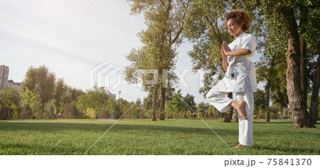 Cute Afro American girl karateka doing exercise outdoors 75841370