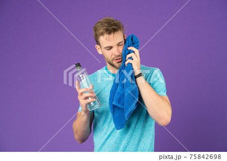 Athlete in blue tshirt and shorts with towel after training.  75842698