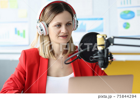 Woman with headphones in front of microphone at work table 75844294