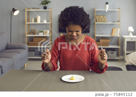 African american woman with disgusting grimace looking at apple piece on plate African american woman with disgusting grimace looking at apple piece on plate 75845112