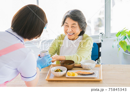 食事にお茶を出す介護士 75845343