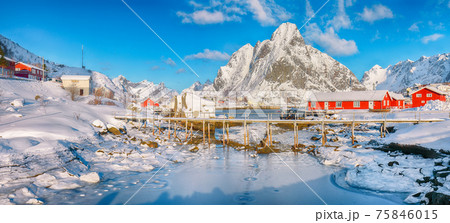 Fabulous winter sunny view on Reine Village and footbridge above Gravdalbukta bay with cracked ice 75846015