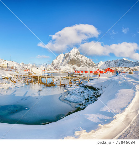 Fabulous winter sunny view on Reine Village and footbridge above Gravdalbukta bay with cracked ice 75846034