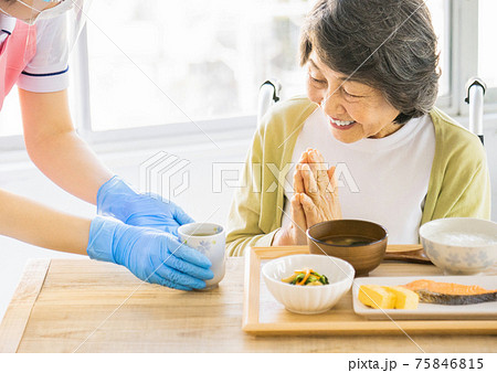 食事にお茶を出す介護士 75846815