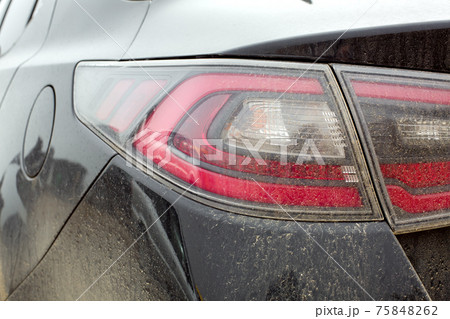 taillight with a red brake light and a turn signal covered with a layer of dust and dry dirt close-up. 75848262